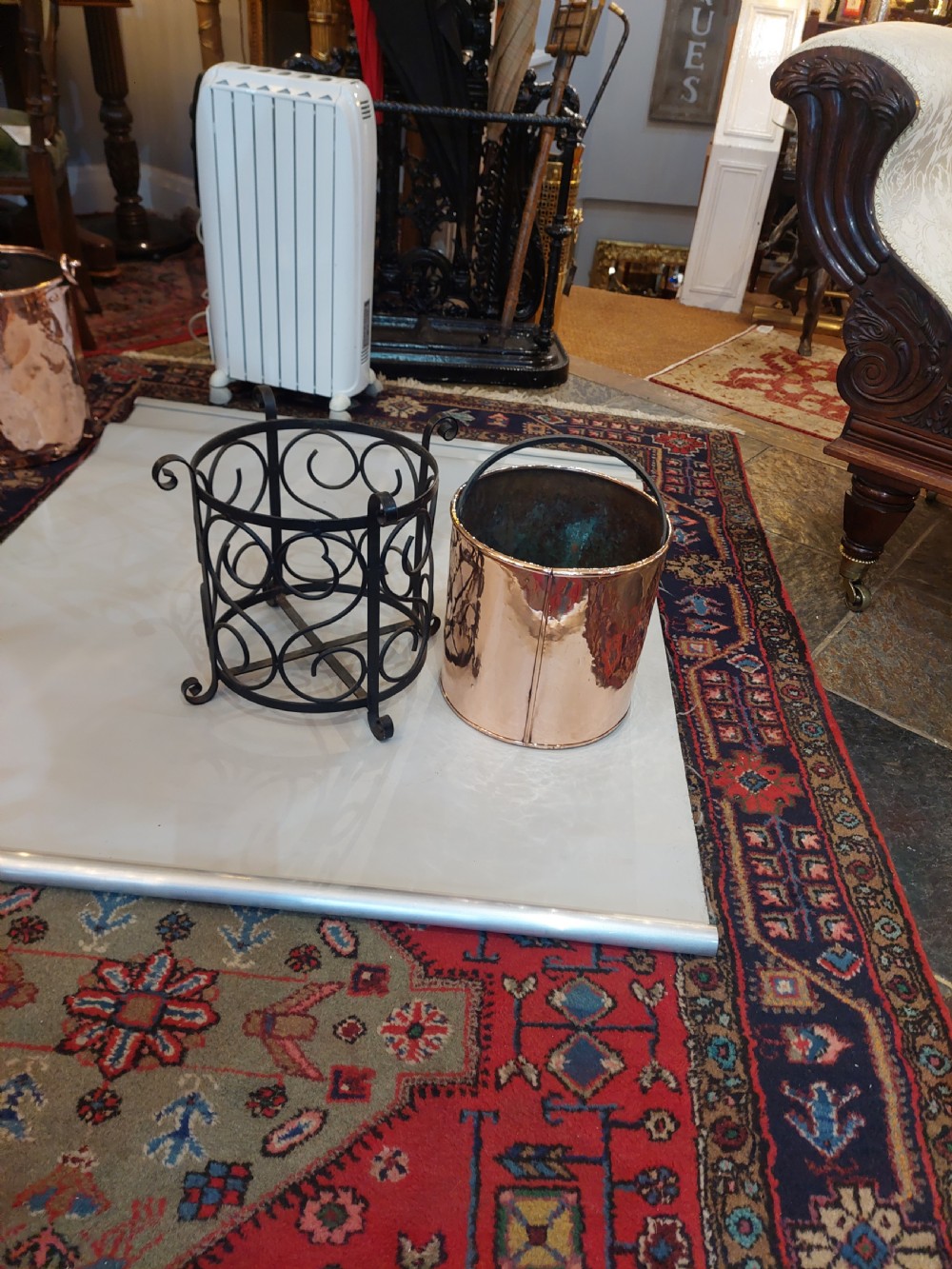 A cylindrical copper bucket set within a black wrought iron frame featuring scroll motifs and a curved carrying handle. View VII
