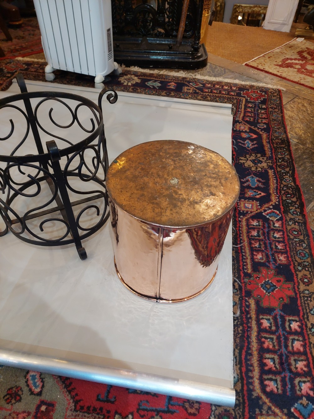 A cylindrical copper bucket set within a black wrought iron frame featuring scroll motifs and a curved carrying handle. View VIII