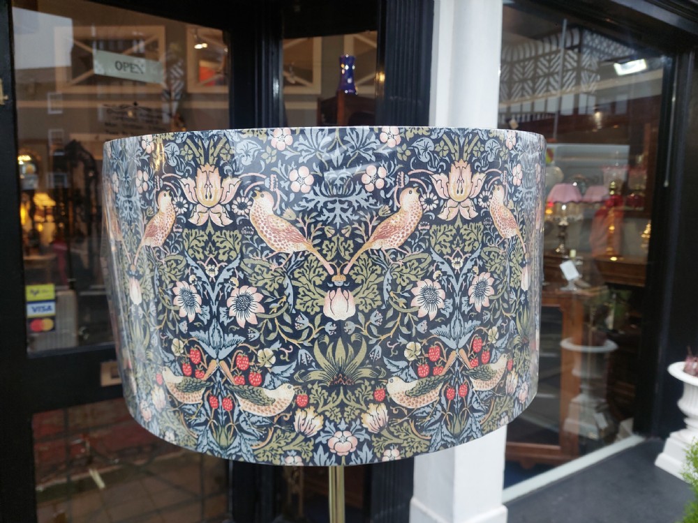 An Art Nouveau brass standard floor lamp featuring curved organic metalwork on a tripod base topped with a patterned floral fabric drum shade. View VIII
