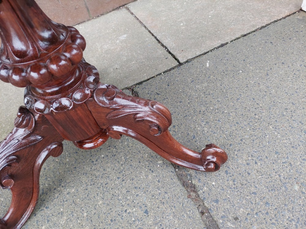 A late Victorian revolving piano stool featuring a carved rosewood tripod base and a circular padded seat with floral embroidery. View II