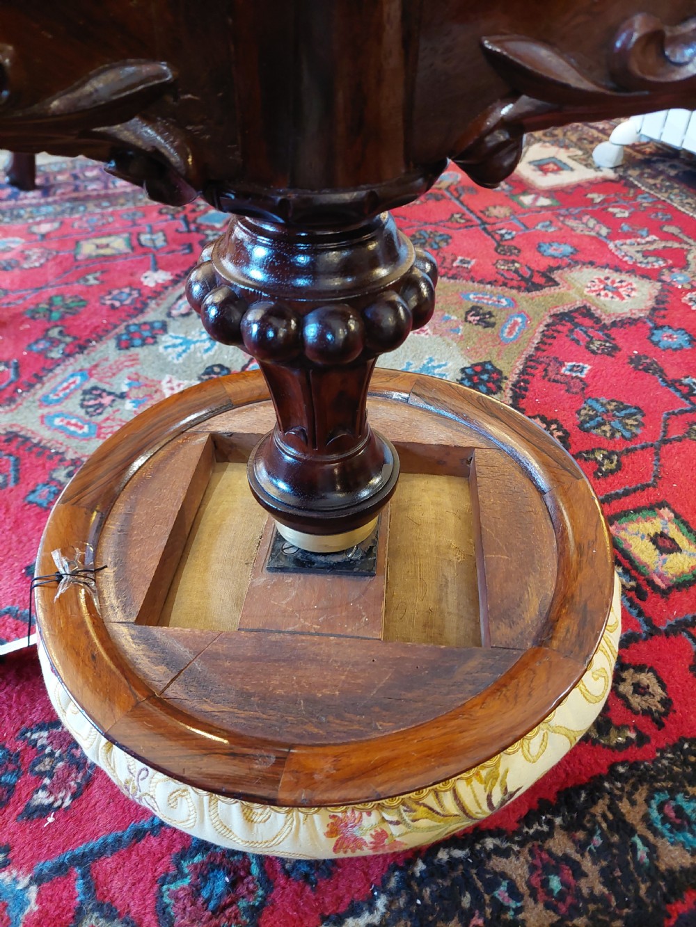 A late Victorian revolving piano stool featuring a carved rosewood tripod base and a circular padded seat with floral embroidery. View VII