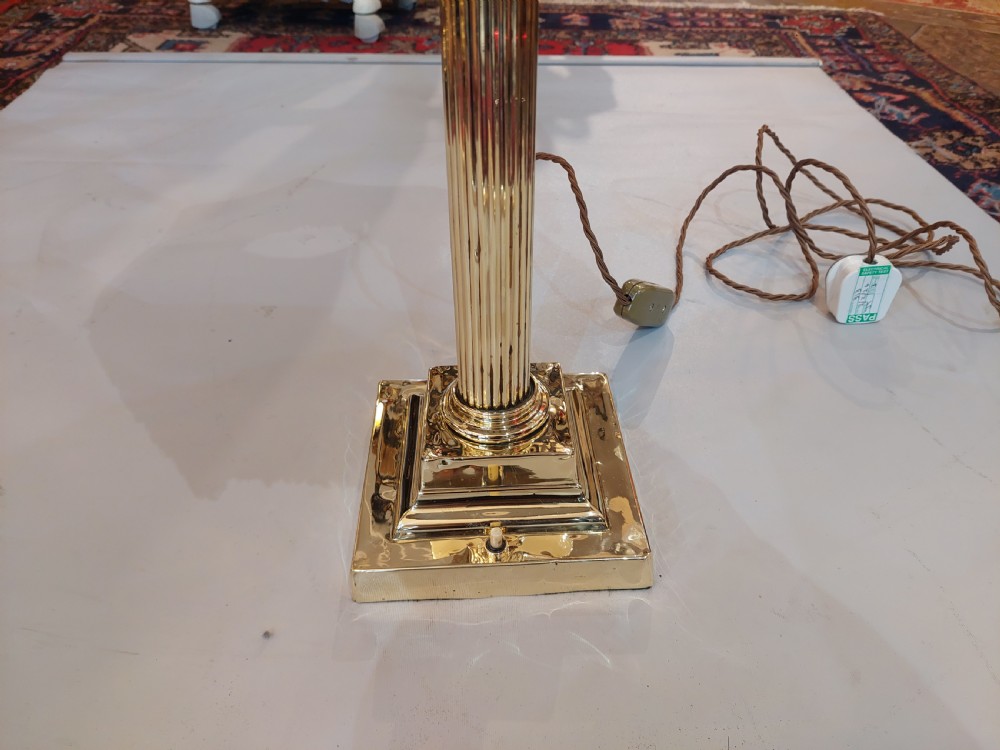 An early 20th-century brass Corinthian column table lamp with a stepped square base and a dome-shaped patterned silk shade featuring fringed tassels. View III