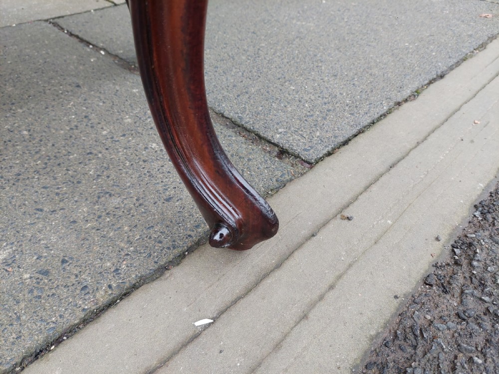A Victorian mahogany stool featuring dark buttoned black leather upholstery with brass studding and four carved cabriole legs. View VI