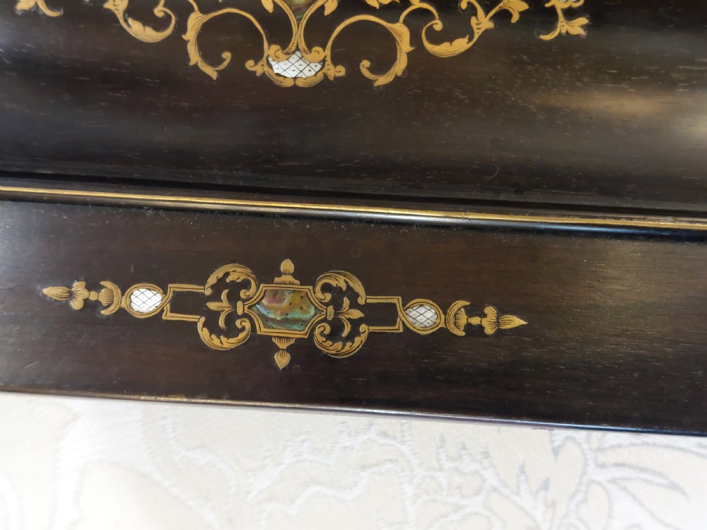 A mid-19th-century dark coromandel wood inkstand desk tidy featuring floral inlay, a pen trough, two lidded compartments, and a central glass inkwell. View VII
