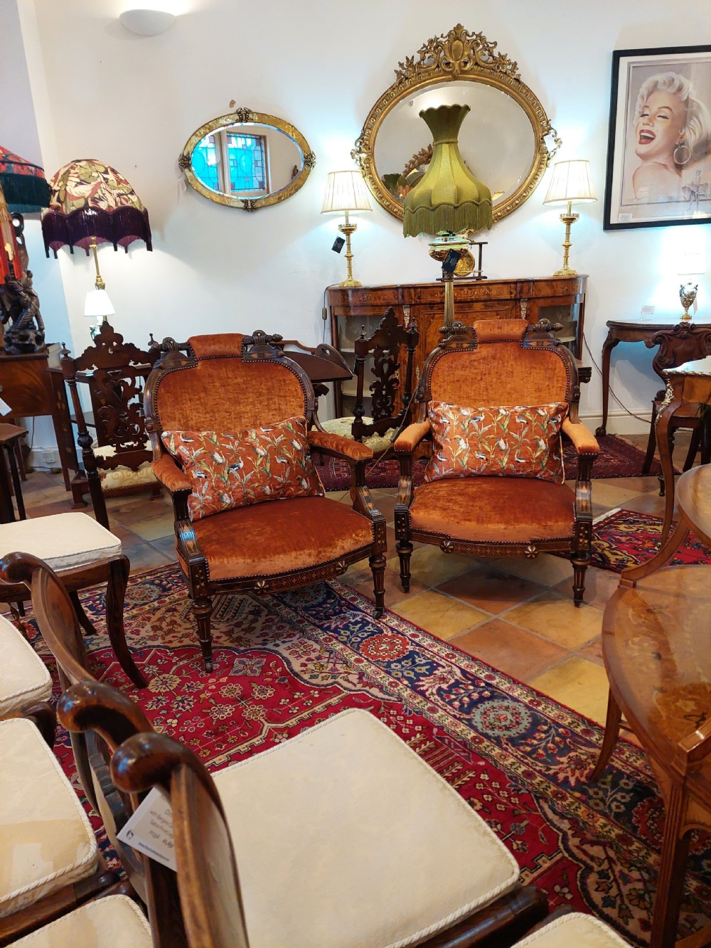 Pair of Victorian rosewood easy armchairs with terracotta velvet upholstery, parcel gilt inlay, turned legs, and decorative patterned cushions. View II