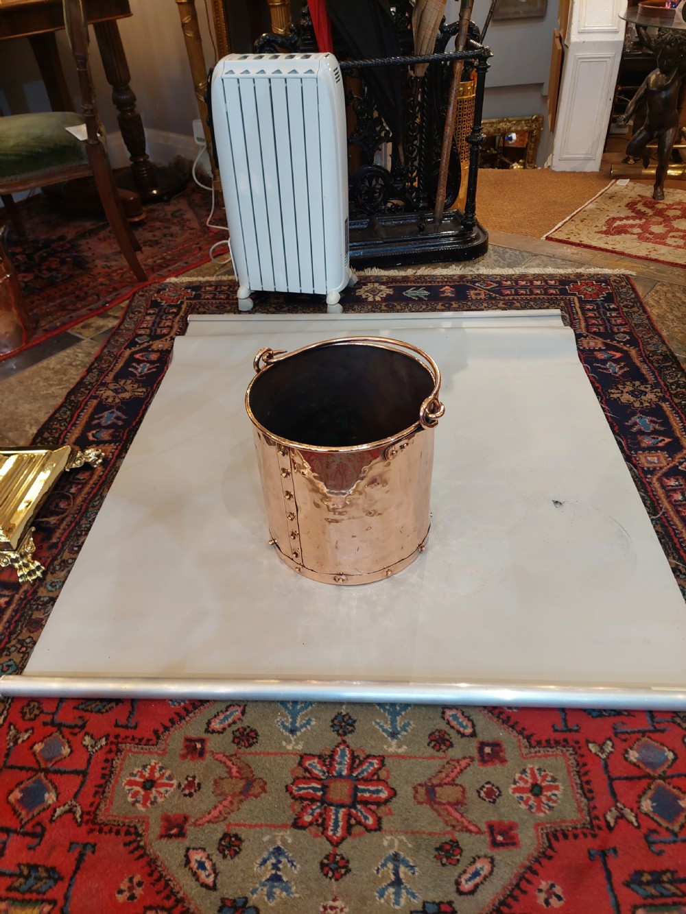 A cylindrical copper coal bucket featuring vertical riveted seams and metallic carrying rings attached to the upper rim. View II