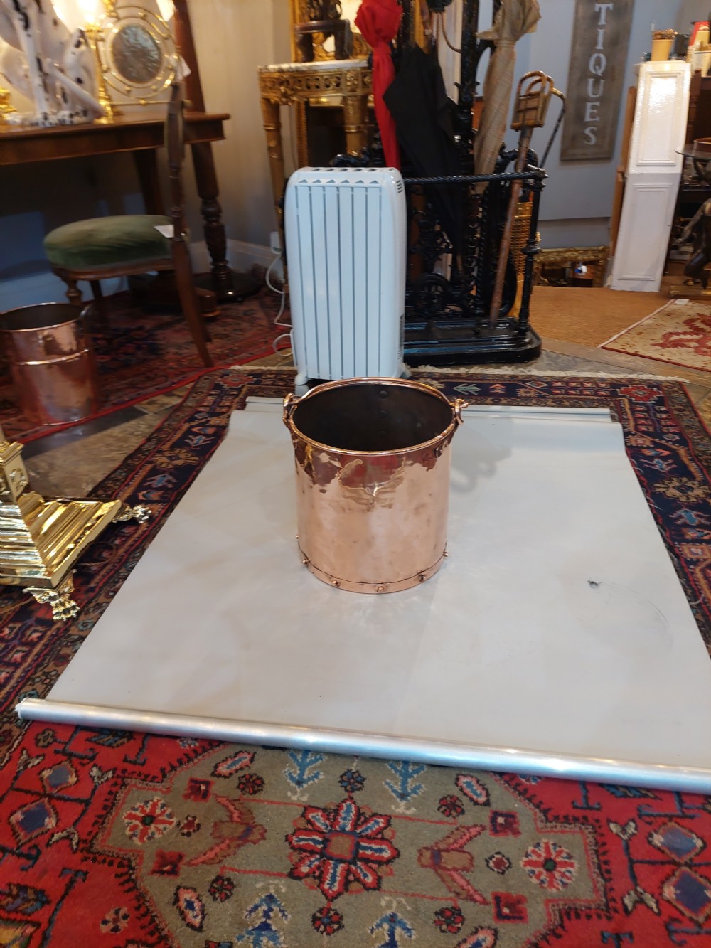 A cylindrical copper coal bucket featuring vertical riveted seams and metallic carrying rings attached to the upper rim. View VII