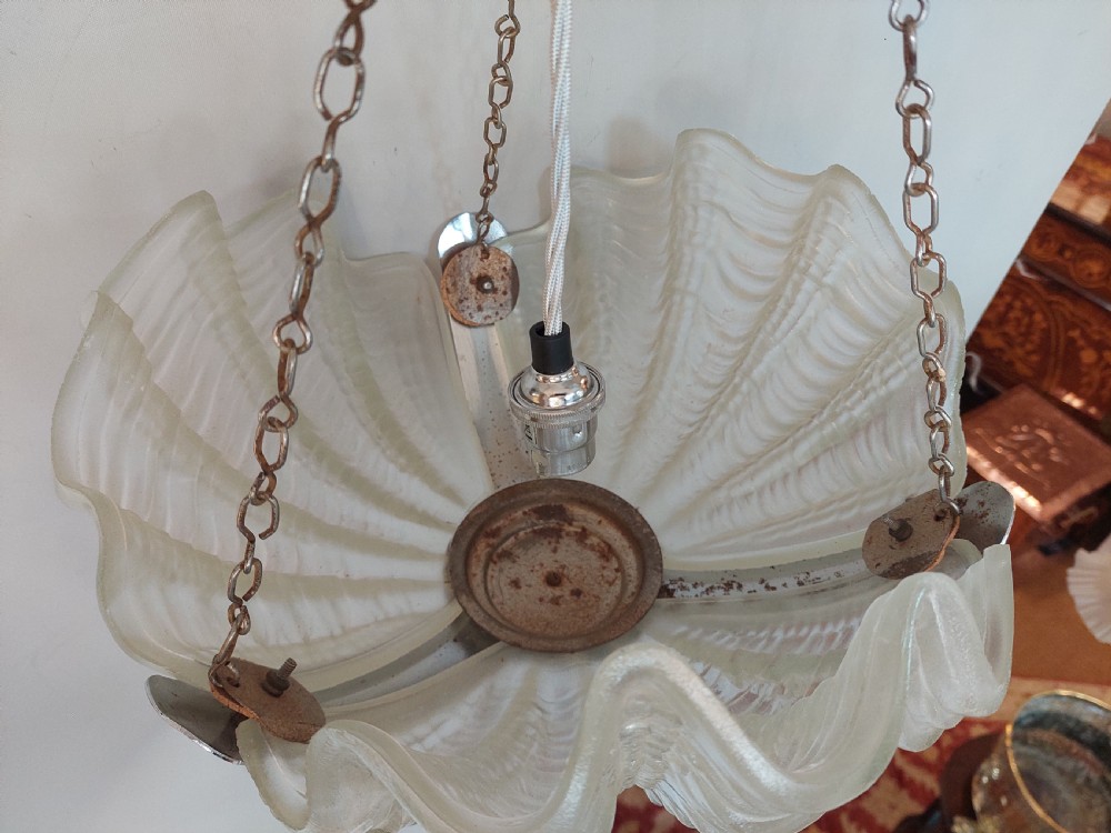 A three-piece Art Deco lighting suite comprising a hanging central shell pendant light and two matching wall sconces made of moulded frosted glass set in chrome mounts. View XI