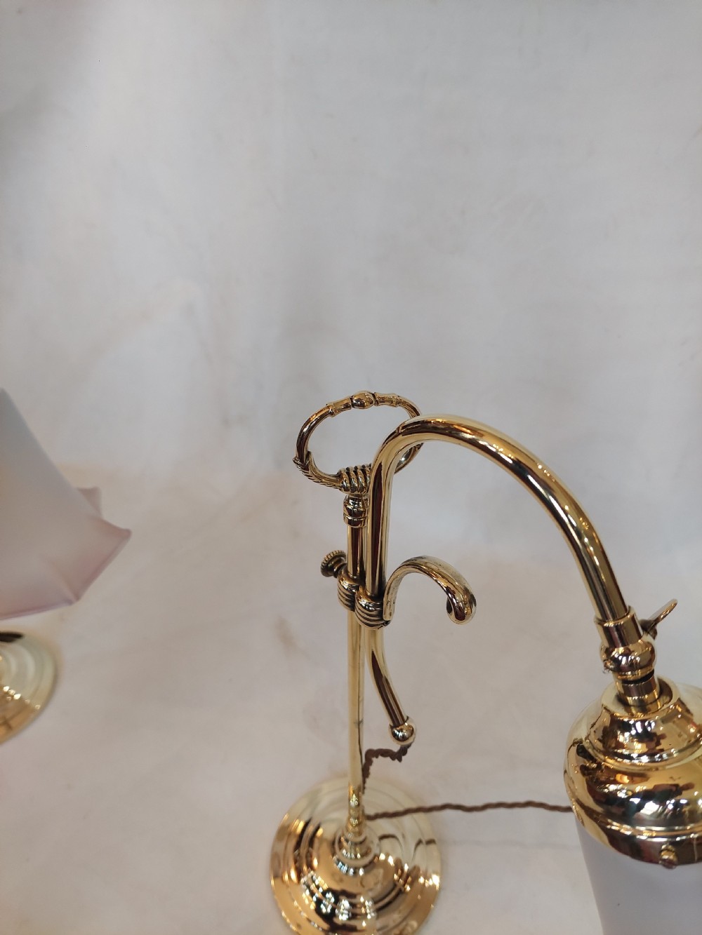 A pair of polished brass swan neck desk lamps with curved stems and frosted glass shades featuring pink fluted rims. View II