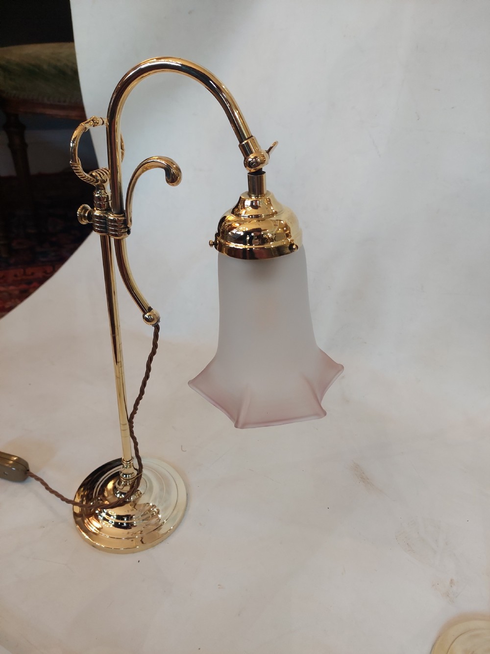 A pair of polished brass swan neck desk lamps with curved stems and frosted glass shades featuring pink fluted rims. View III