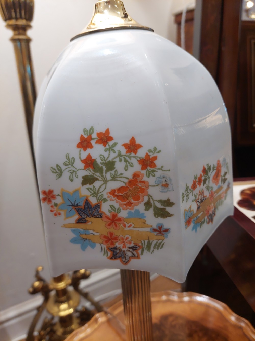A polished brass table lamp designed as a fluted Corinthian column on a stepped square base, topped with a scalloped cream fabric shade decorated with embroidered floral motifs. View IV