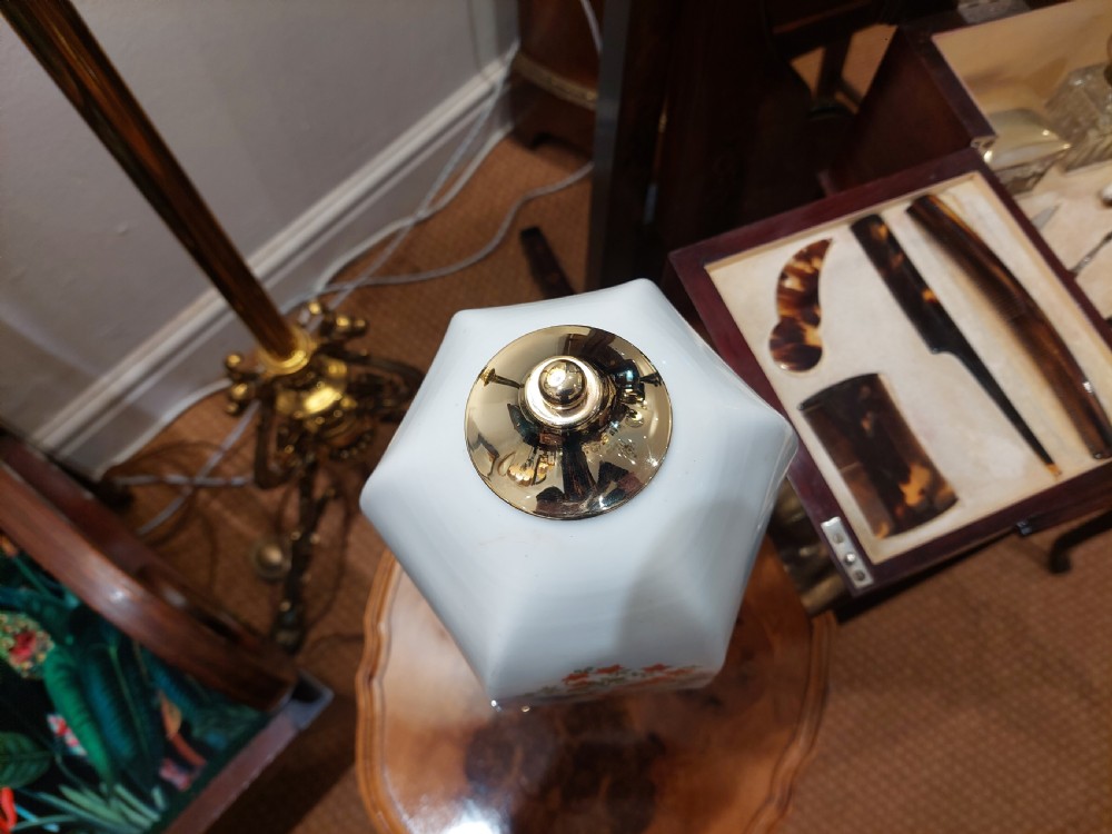 A polished brass table lamp designed as a fluted Corinthian column on a stepped square base, topped with a scalloped cream fabric shade decorated with embroidered floral motifs. View VII