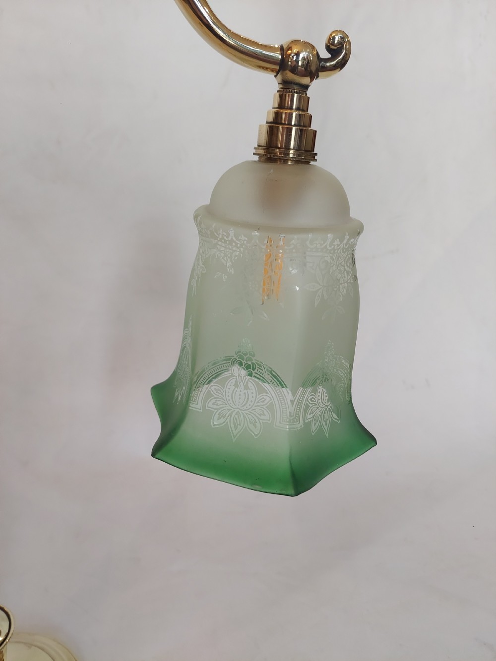 An early twentieth-century polished brass swan neck desk lamp with a turned stem and a frosted glass shade featuring etched detailing and a green ruffled rim. View IV