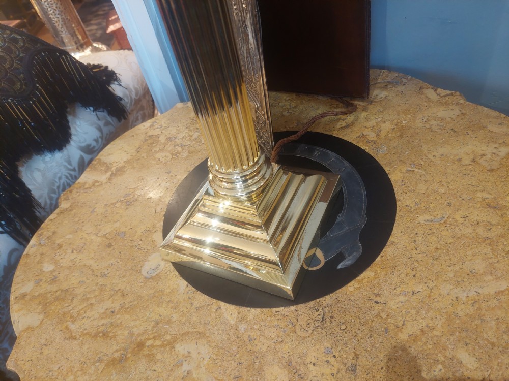An early 20th-century brass table lamp featuring a reeded Doric column base and a patterned fabric lampshade with dark blue fringe and crystal drop beads. View IV