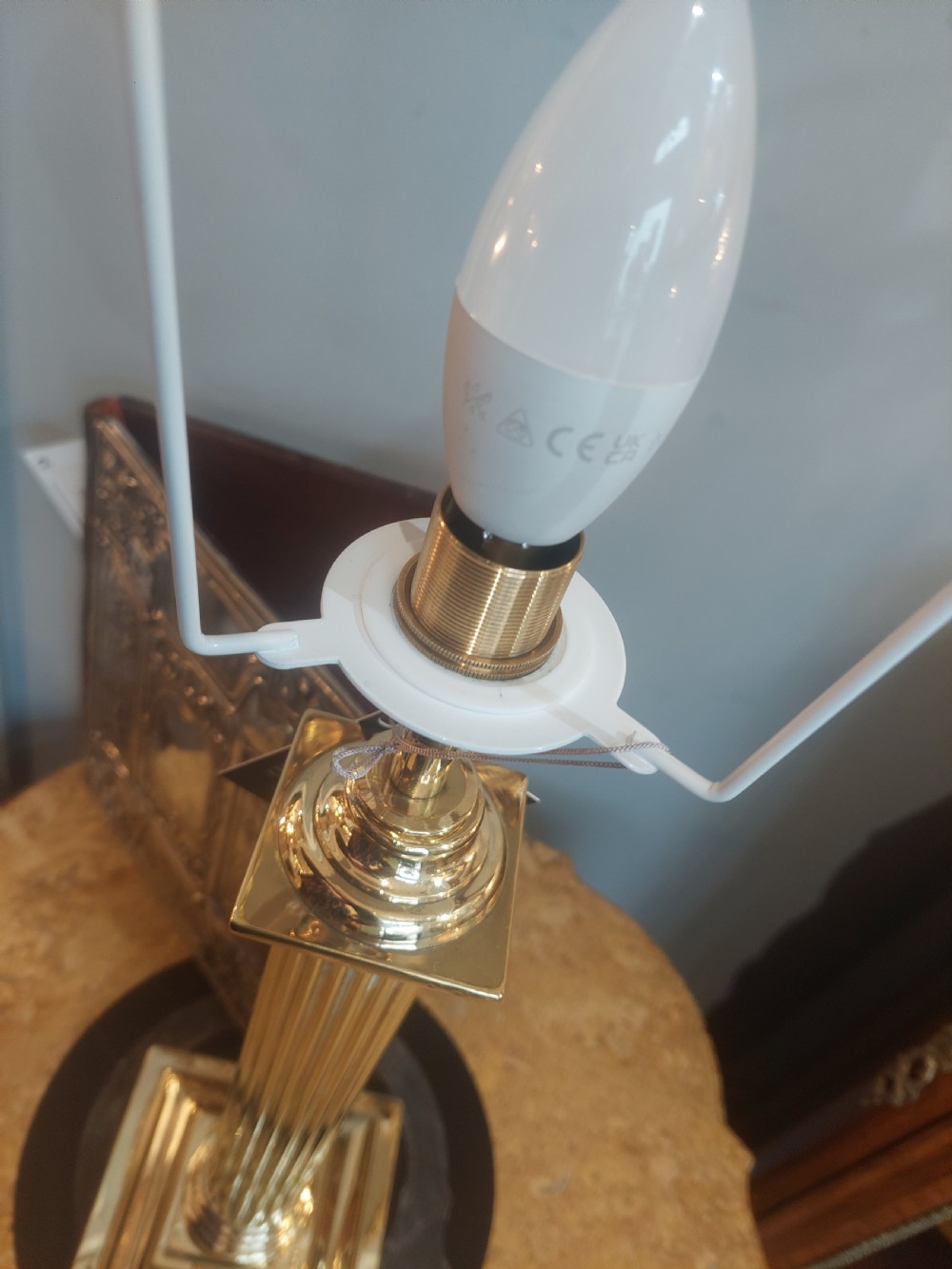 An early 20th-century brass table lamp featuring a reeded Doric column base and a patterned fabric lampshade with dark blue fringe and crystal drop beads. View V
