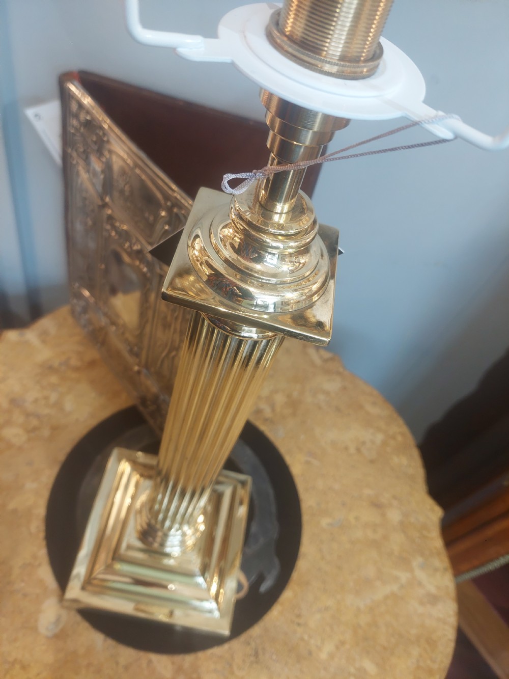 An early 20th-century brass table lamp featuring a reeded Doric column base and a patterned fabric lampshade with dark blue fringe and crystal drop beads. View VI
