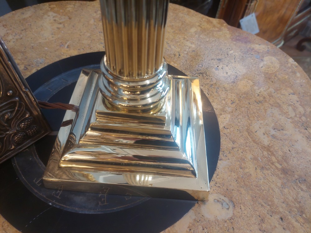 An early 20th-century brass table lamp featuring a reeded Doric column base and a patterned fabric lampshade with dark blue fringe and crystal drop beads. View VIII