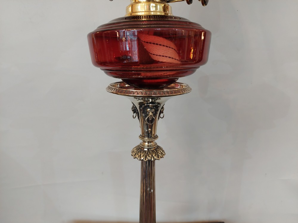 A late Victorian silver-plated oil lamp featuring a fluted column stem, a red cranberry glass reservoir, a brass burner, and a frosted etched glass shade. View IV