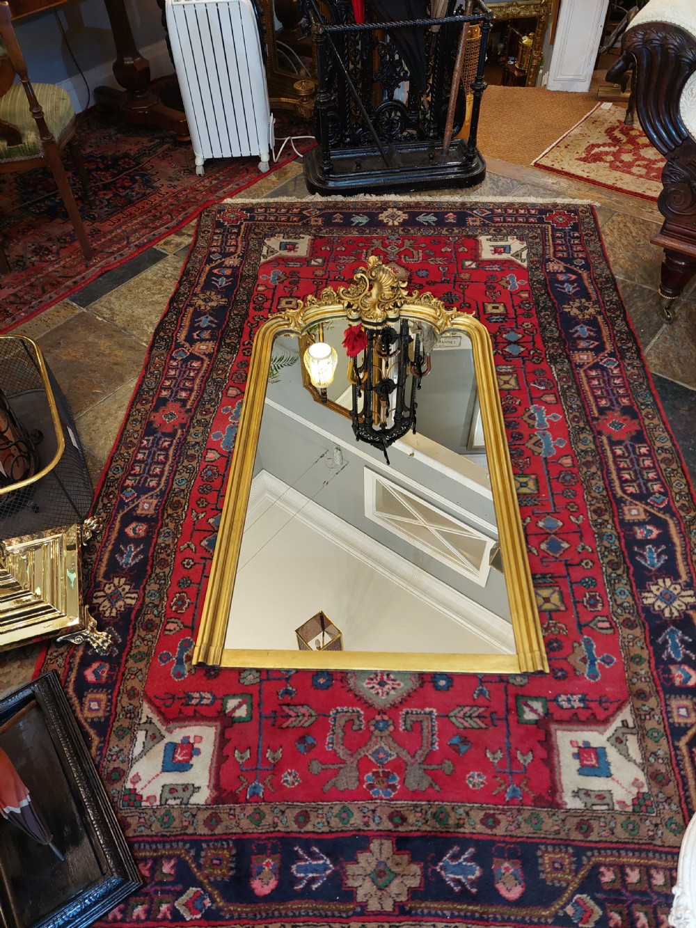 A Victorian giltwood overmantel mirror featuring an arched frame topped with an intricate rococo cresting of acanthus leaves and shell motifs. View II