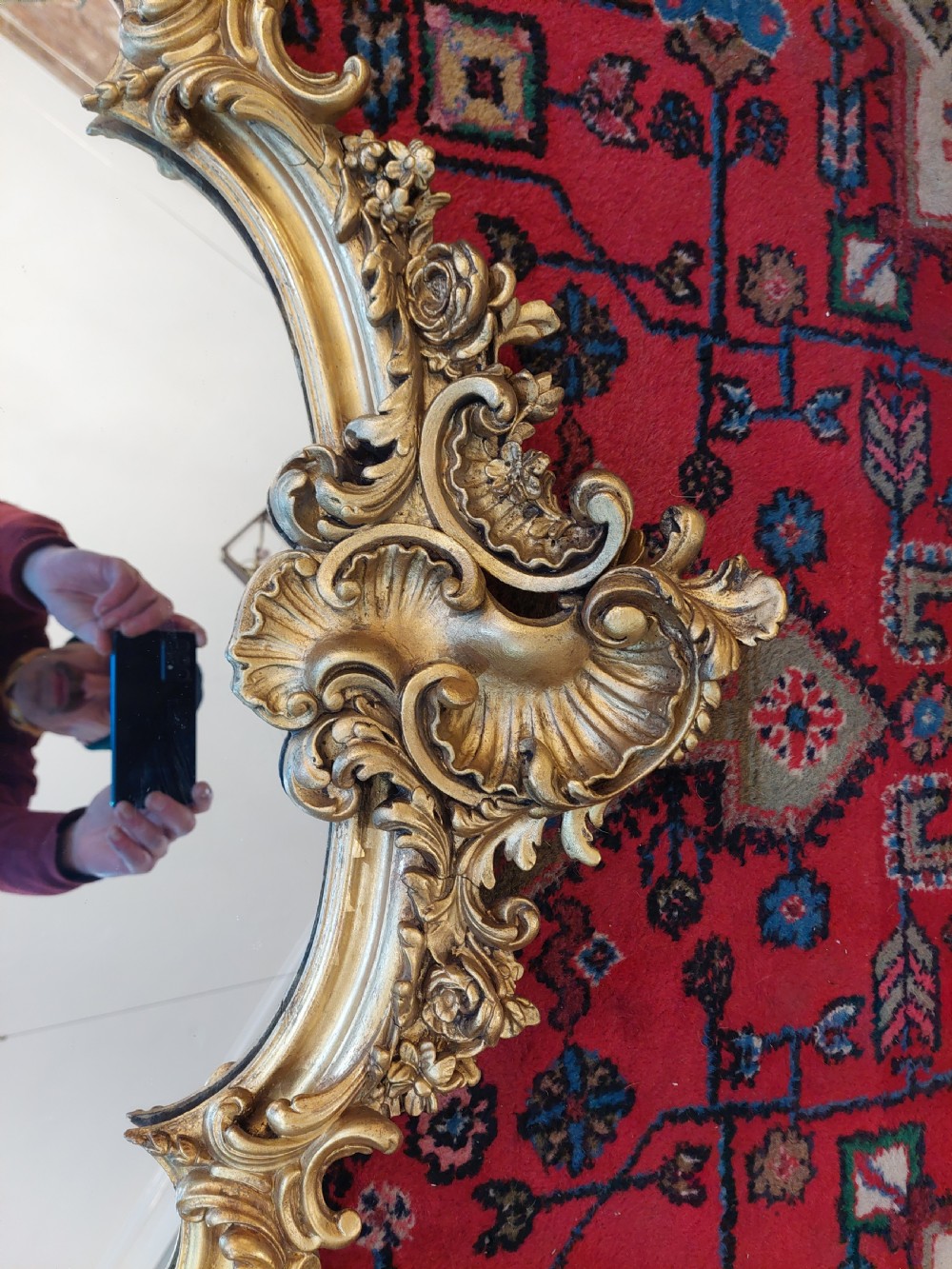 A Victorian giltwood overmantel mirror featuring an arched frame topped with an intricate rococo cresting of acanthus leaves and shell motifs. View V