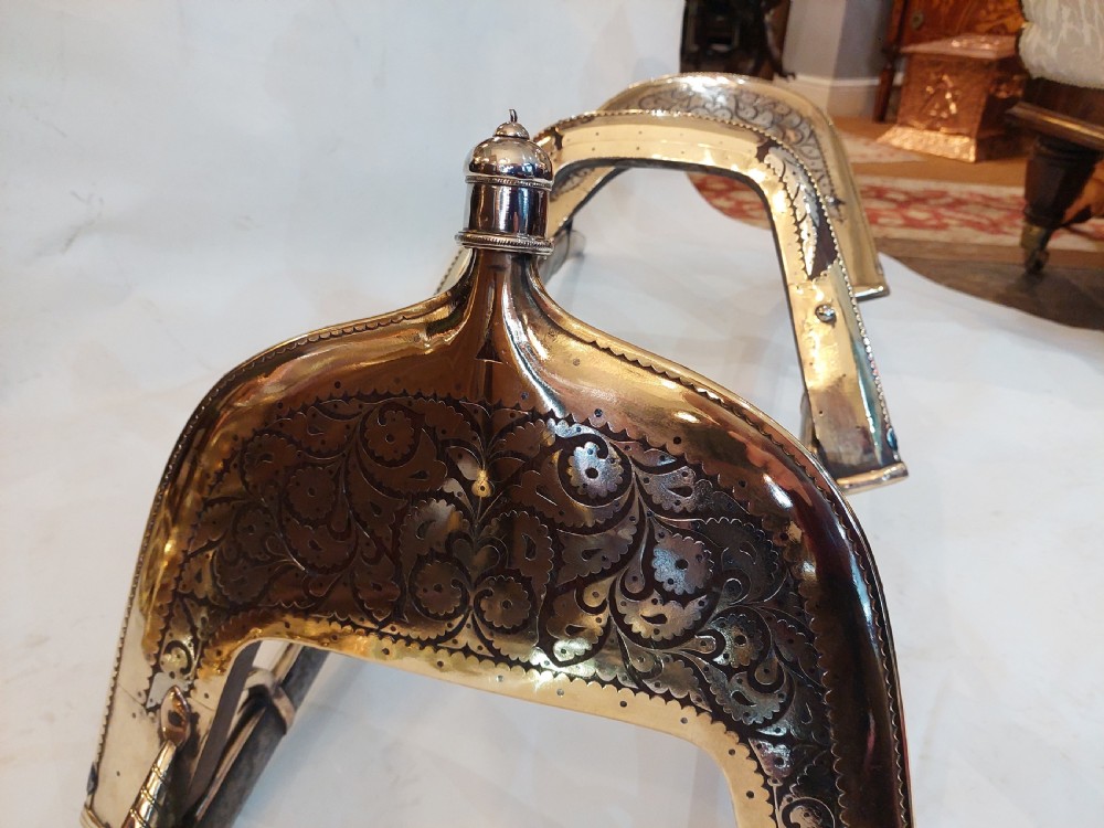 An antique ceremonial camel saddle frame featuring arched pommels clad in chased brass and silvered metal with floral engraving. View II