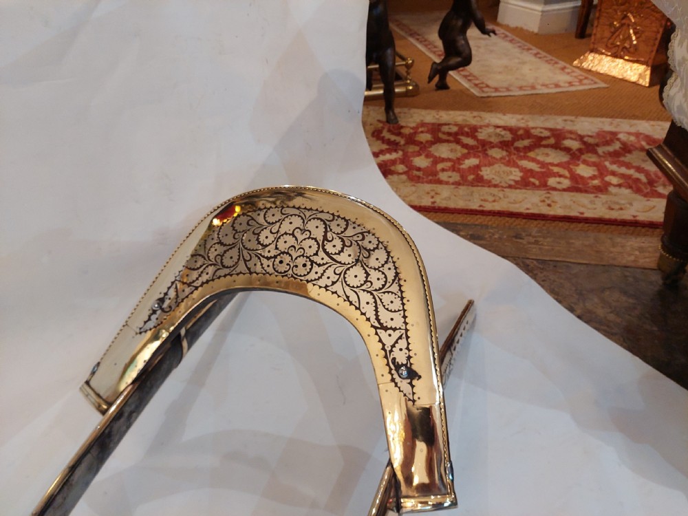 An antique ceremonial camel saddle frame featuring arched pommels clad in chased brass and silvered metal with floral engraving. View V