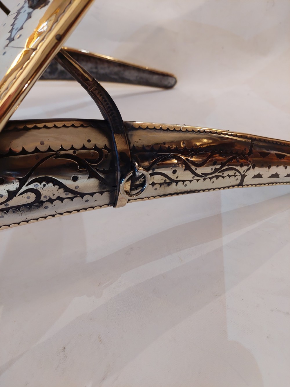 An antique ceremonial camel saddle frame featuring arched pommels clad in chased brass and silvered metal with floral engraving. View VIII