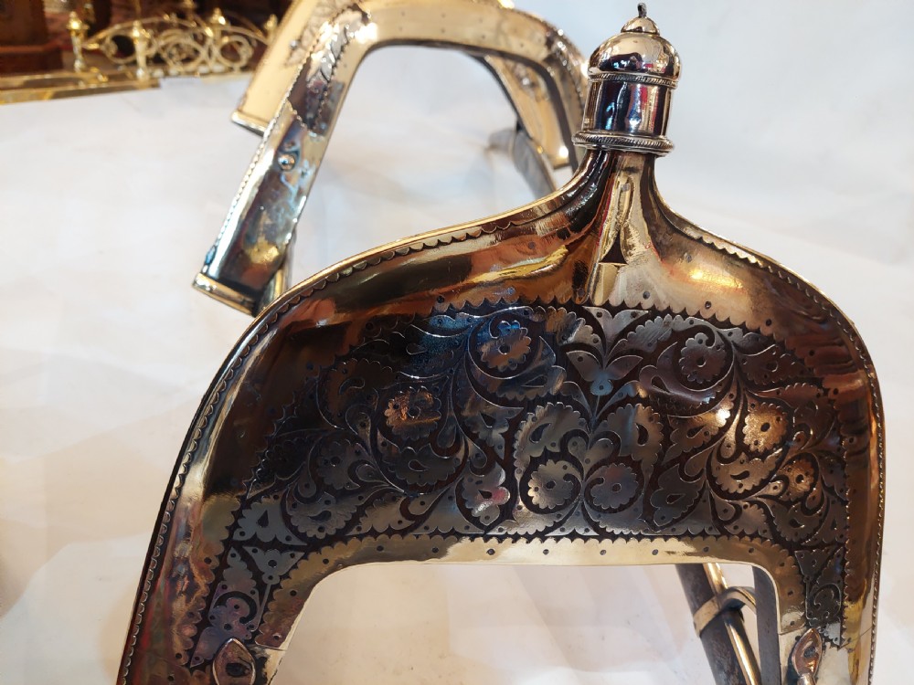 An antique ceremonial camel saddle frame featuring arched pommels clad in chased brass and silvered metal with floral engraving. View IX