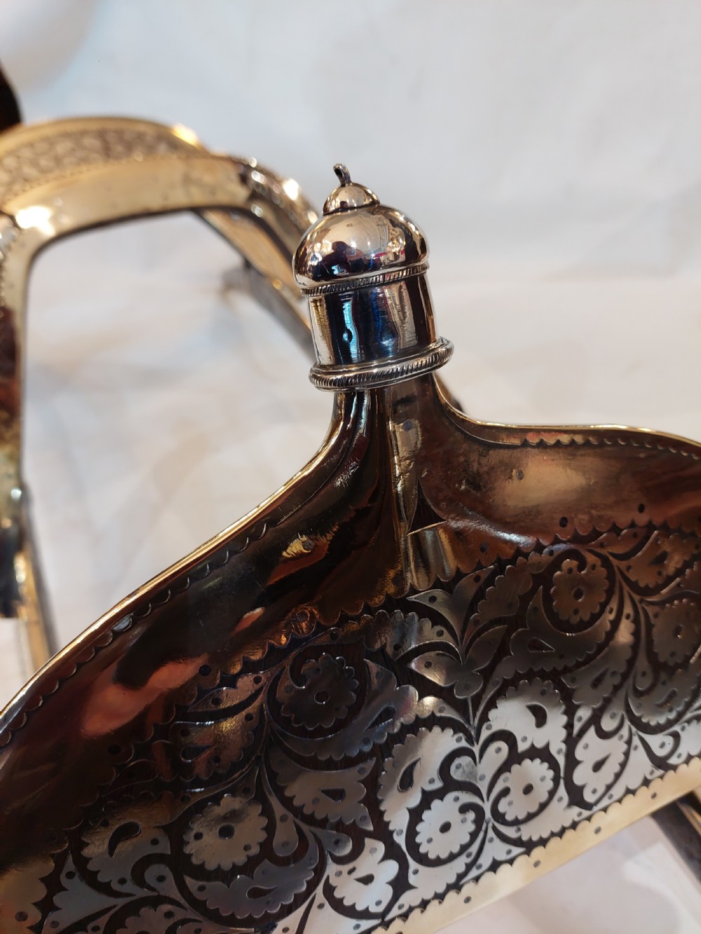 An antique ceremonial camel saddle frame featuring arched pommels clad in chased brass and silvered metal with floral engraving. View X