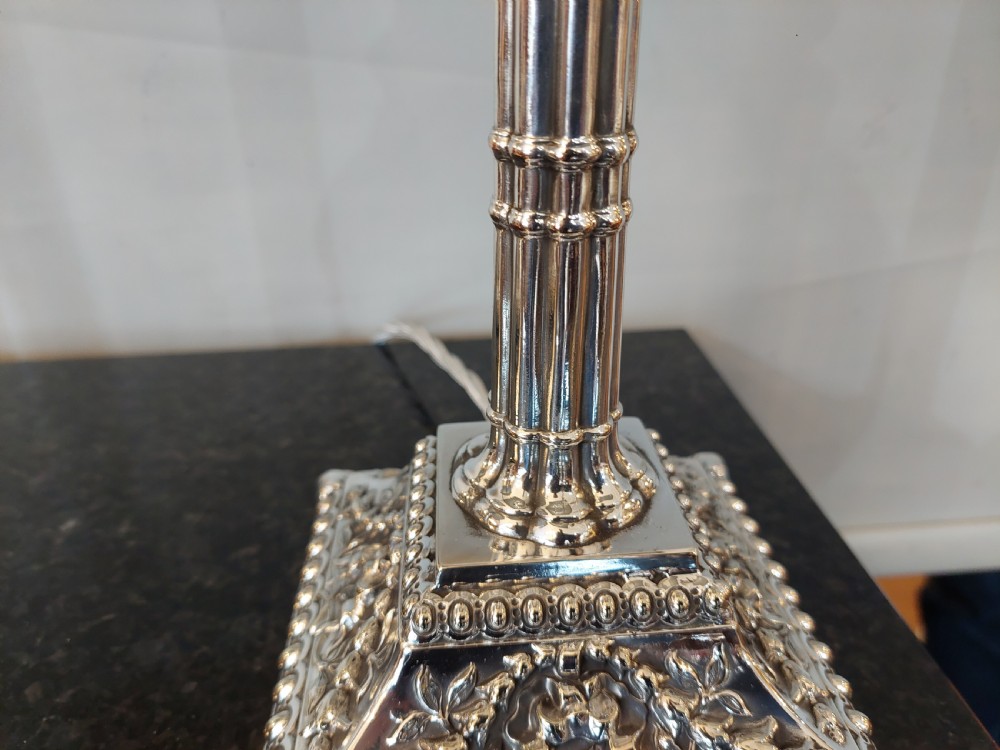A pair of silver-plated table lamps designed as fluted classical columns with square relief-carved bases and cream square fabric lampshades. View IV