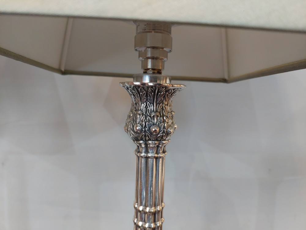 A pair of silver-plated table lamps designed as fluted classical columns with square relief-carved bases and cream square fabric lampshades. View V