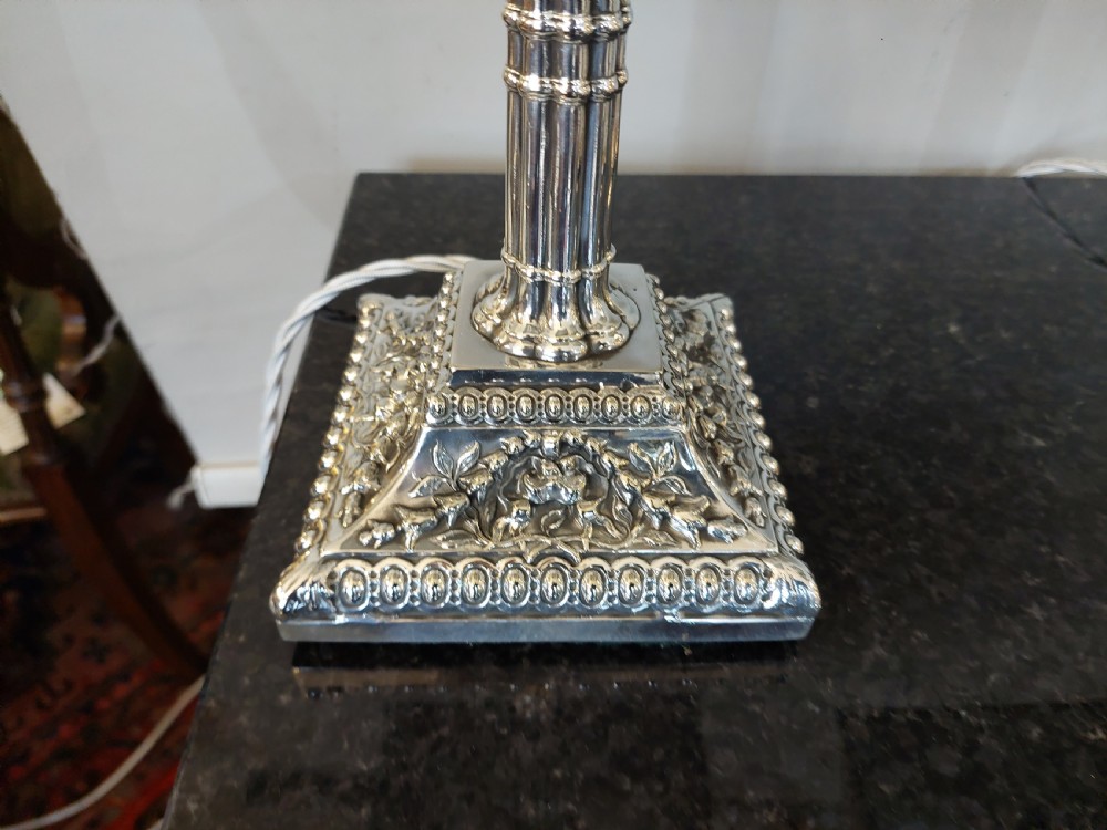A pair of silver-plated table lamps designed as fluted classical columns with square relief-carved bases and cream square fabric lampshades. View VI