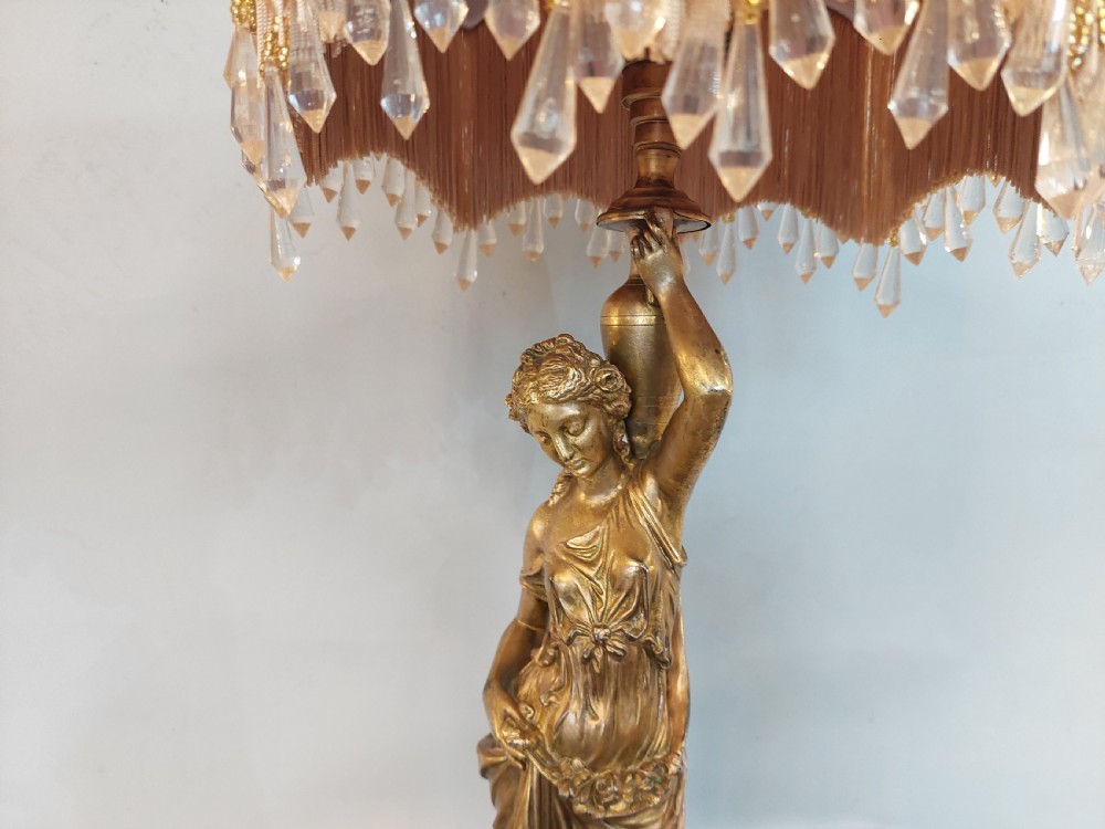 An antique Victorian cold-painted bronze table lamp shaped as a classical standing female figure on a green marble base, topped with a pink silk fringed shade. View II
