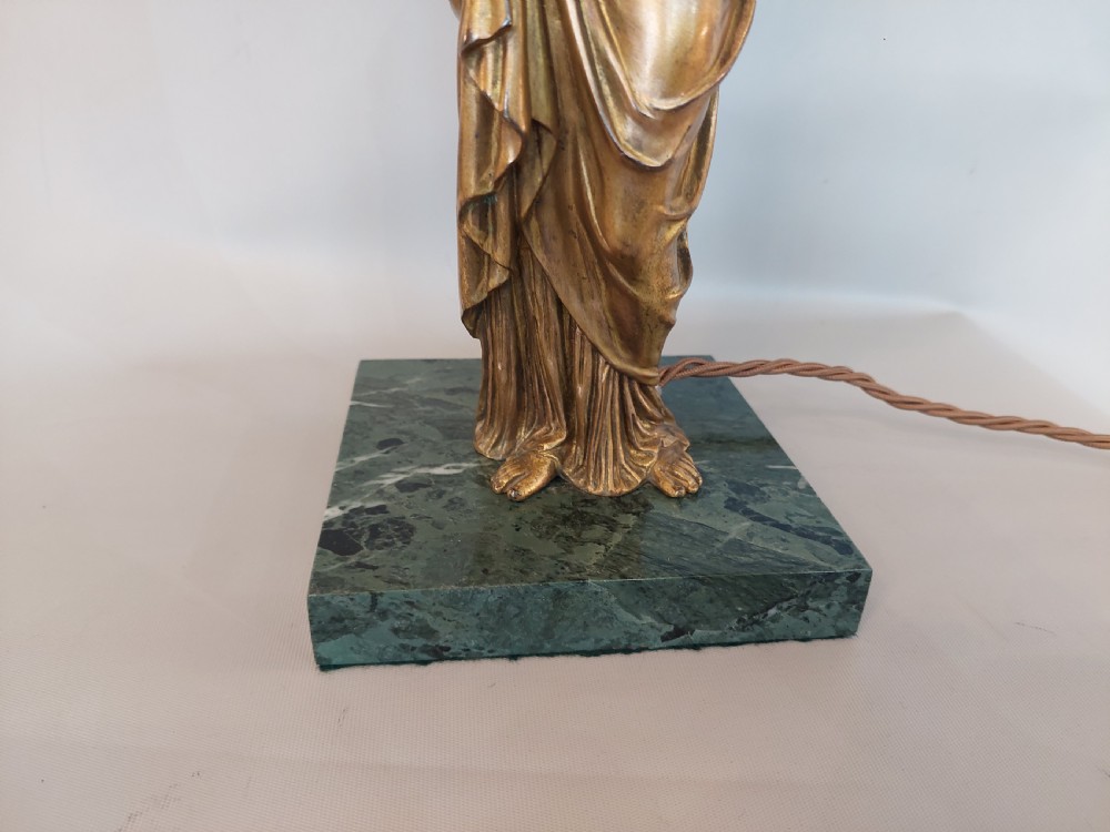 An antique Victorian cold-painted bronze table lamp shaped as a classical standing female figure on a green marble base, topped with a pink silk fringed shade. View V