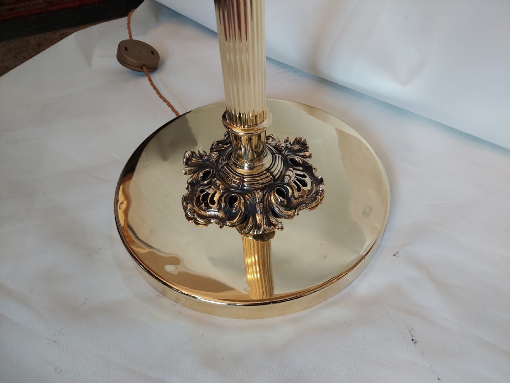 A pair of 1920s polished brass standard floor lamps featuring reeded columns, decorative cast bases, and pleated fabric shades. View II