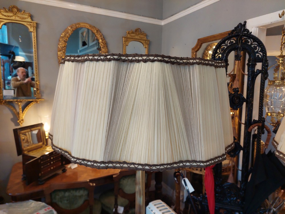 A pair of 1920s polished brass standard floor lamps featuring reeded columns, decorative cast bases, and pleated fabric shades. View IV