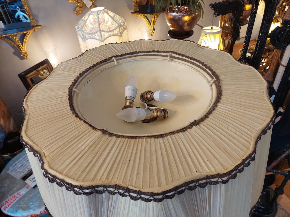 A pair of 1920s polished brass standard floor lamps featuring reeded columns, decorative cast bases, and pleated fabric shades. View V
