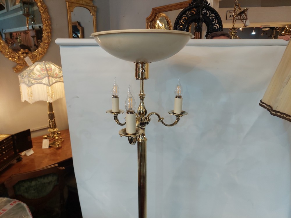 A pair of 1920s polished brass standard floor lamps featuring reeded columns, decorative cast bases, and pleated fabric shades. View X