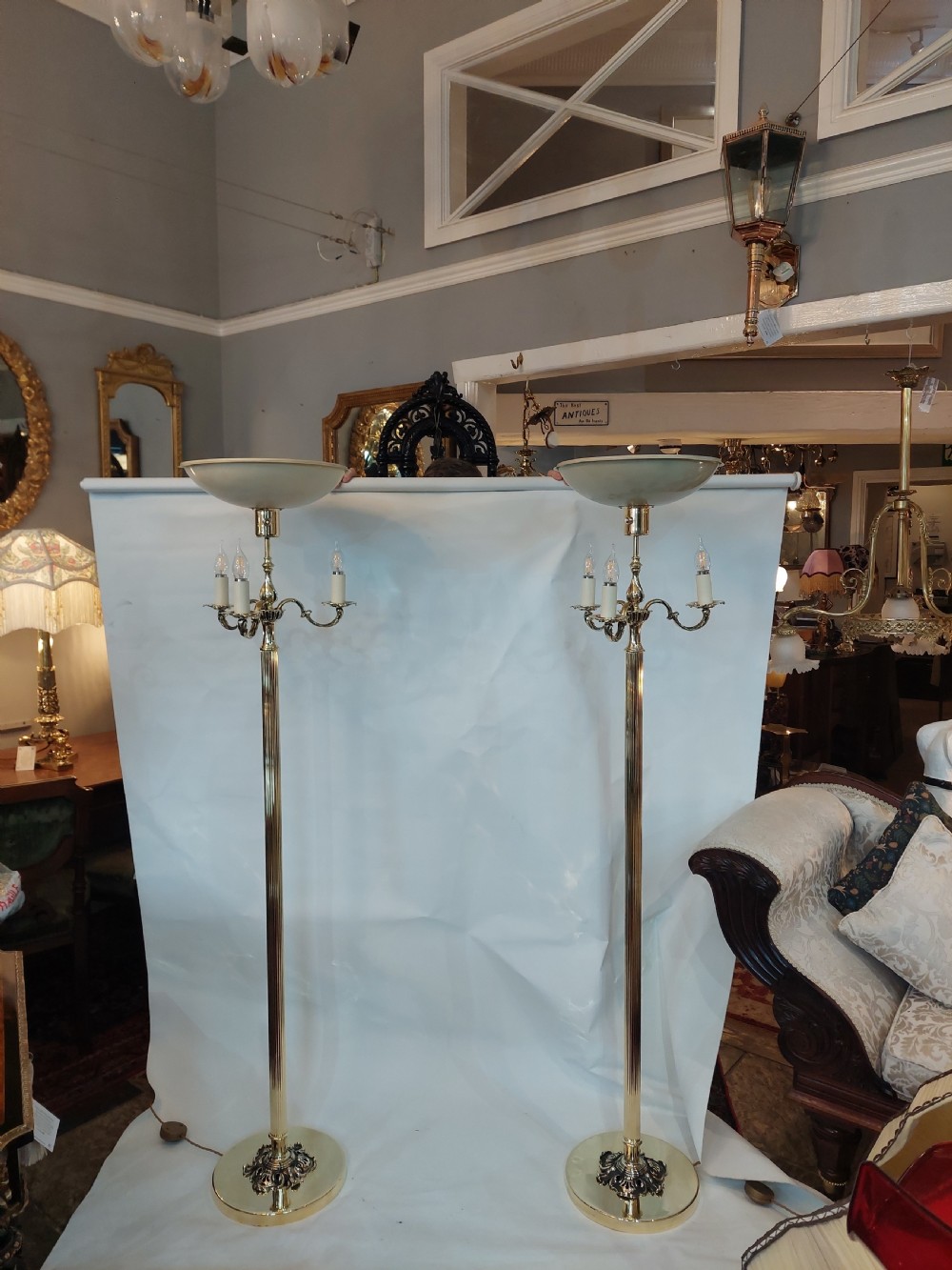 A pair of 1920s polished brass standard floor lamps featuring reeded columns, decorative cast bases, and pleated fabric shades. View XI