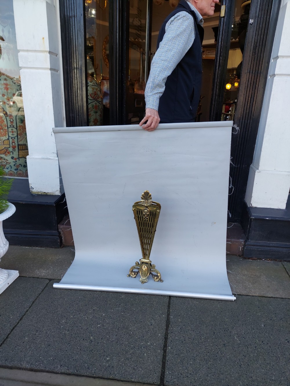 A Victorian folding brass fireplace screen shaped like an open fan with pierced filigree blades mounted on a cast base. View VI
