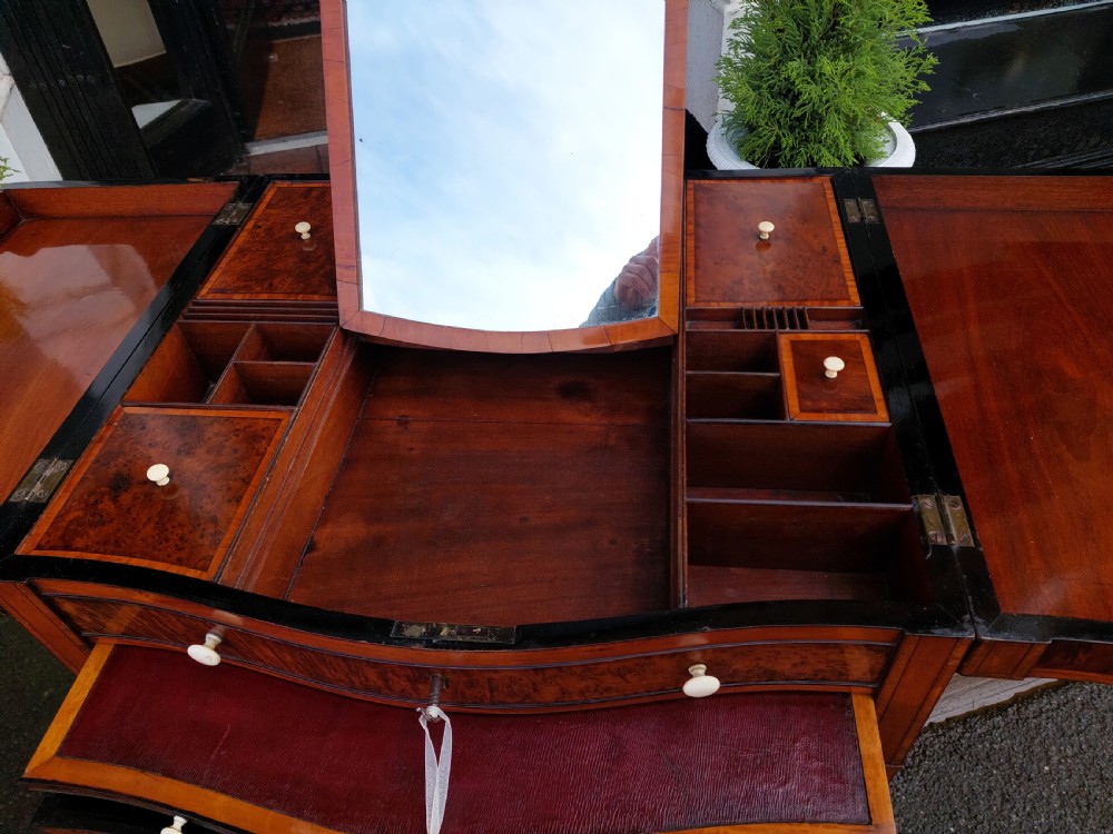 A George III satinwood and mahogany gentlemans wash stand with extended hinged top flaps, an upright central mirror, and tapered inlaid legs on brass castors. View III