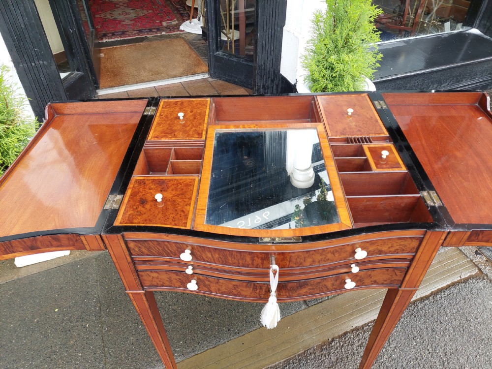A George III satinwood and mahogany gentlemans wash stand with extended hinged top flaps, an upright central mirror, and tapered inlaid legs on brass castors. View VIII