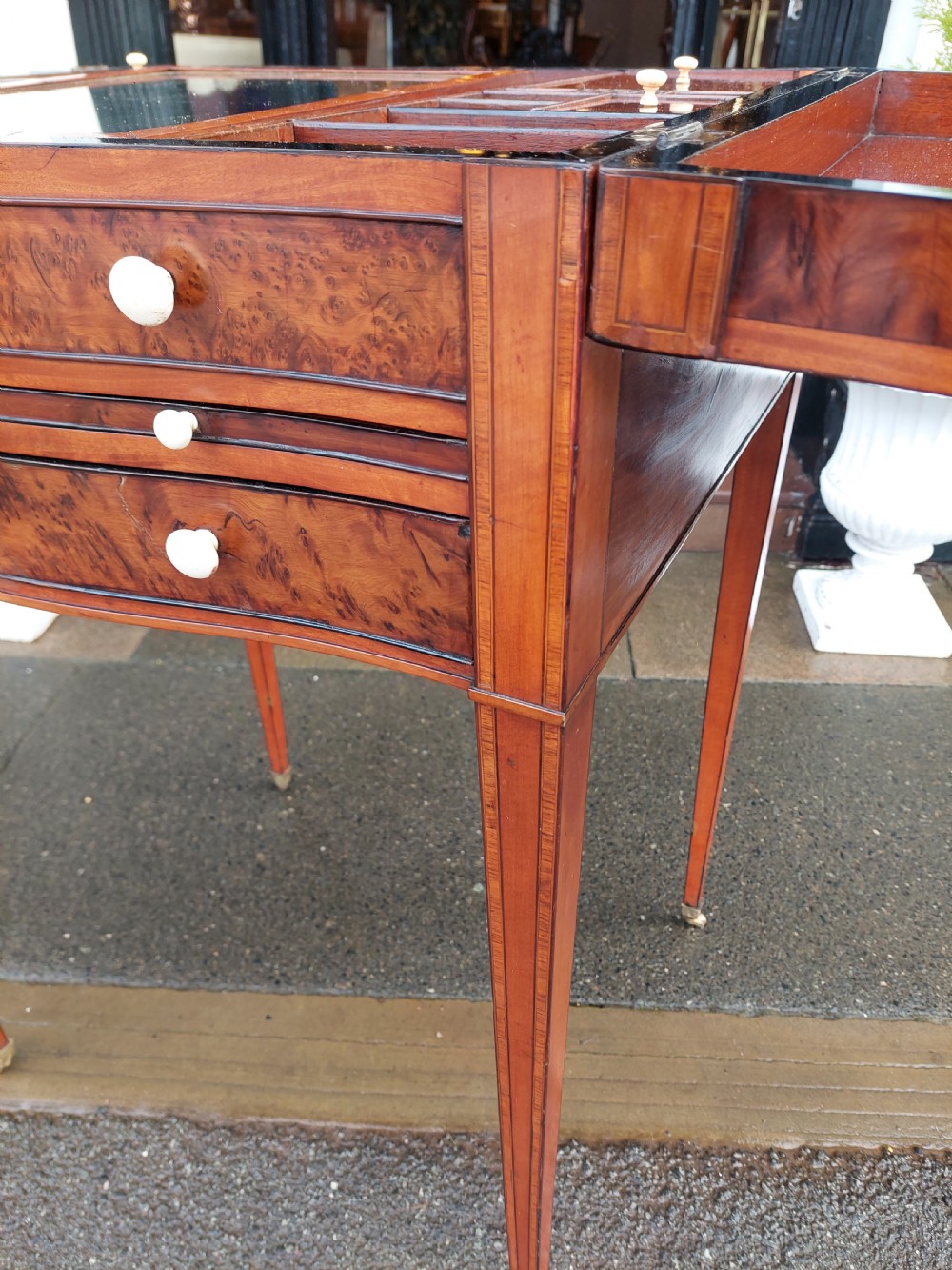 A George III satinwood and mahogany gentlemans wash stand with extended hinged top flaps, an upright central mirror, and tapered inlaid legs on brass castors. View IX