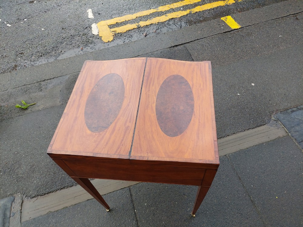 A George III satinwood and mahogany gentlemans wash stand with extended hinged top flaps, an upright central mirror, and tapered inlaid legs on brass castors. View X