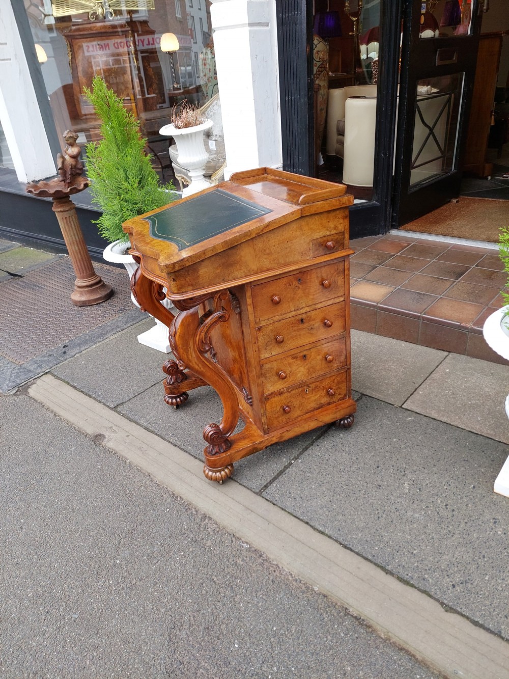 A Victorian burr walnut Davenport desk featuring a green leather sloped writing surface, carved cabriole front supports, and side drawers on castors. View III