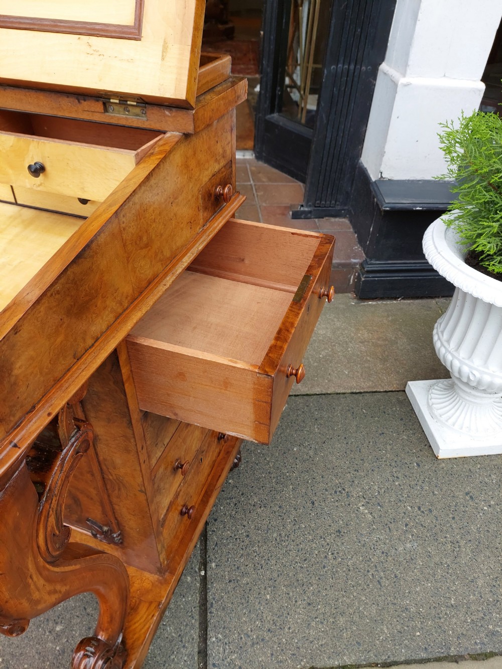 A Victorian burr walnut Davenport desk featuring a green leather sloped writing surface, carved cabriole front supports, and side drawers on castors. View VII