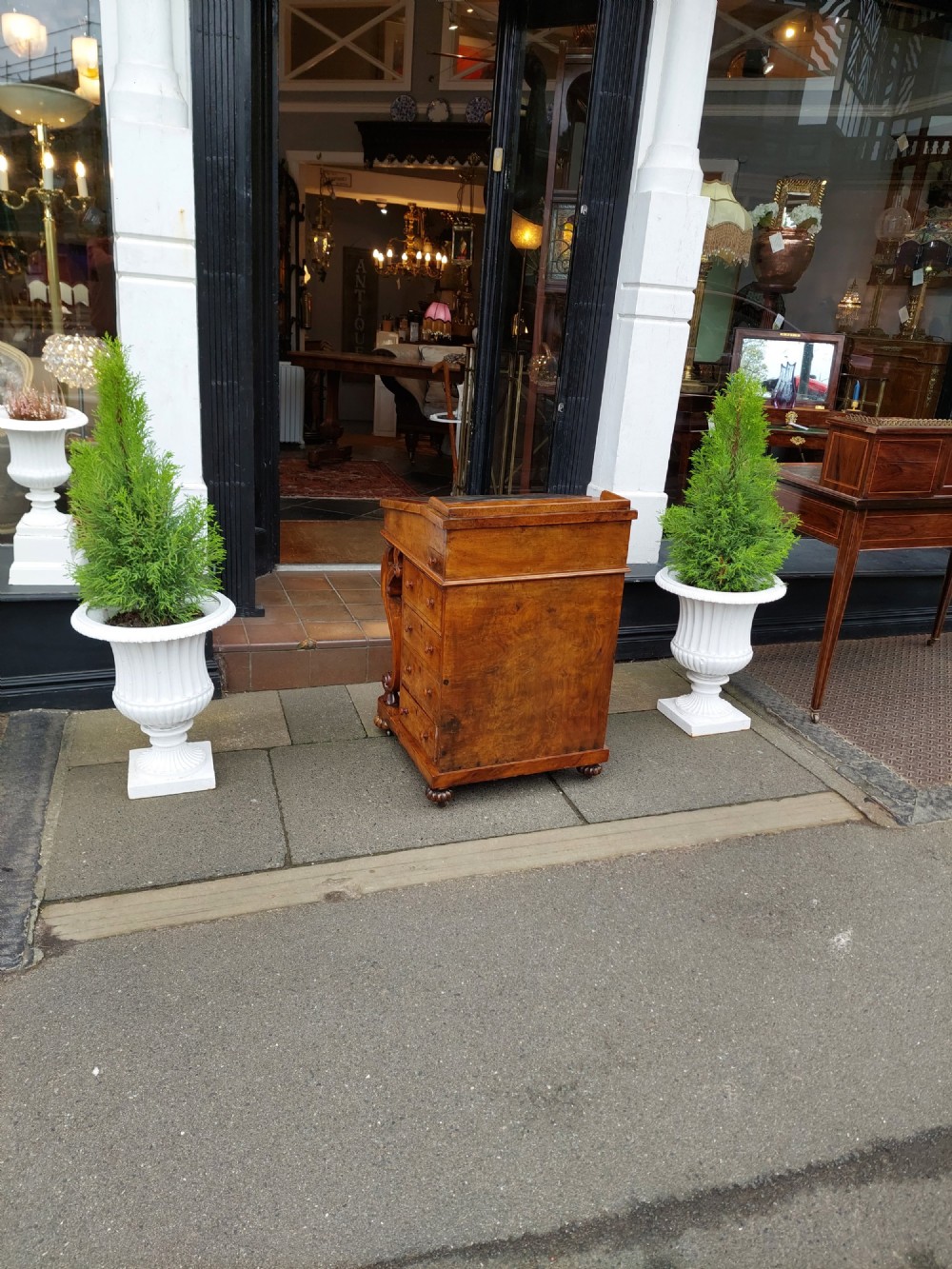 A Victorian burr walnut Davenport desk featuring a green leather sloped writing surface, carved cabriole front supports, and side drawers on castors. View IX