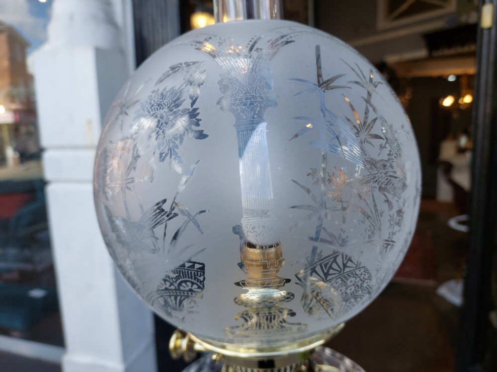 A Victorian brass oil lamp featuring a fluted Corinthian column base, a clear glass reservoir, and an etched spherical glass shade. View IV