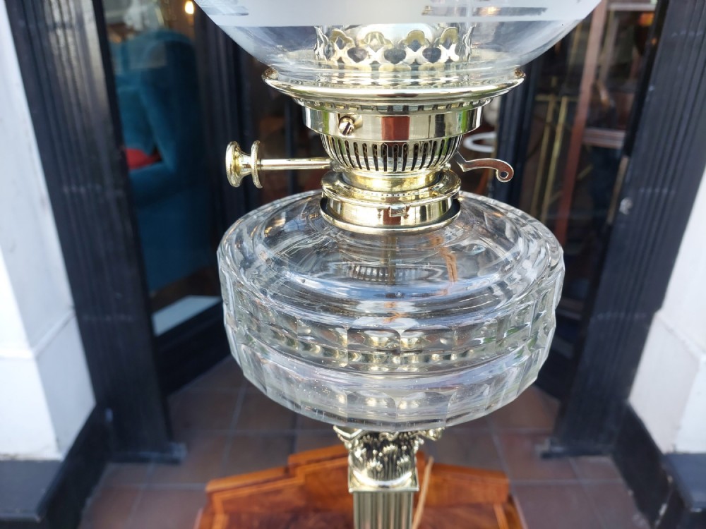A Victorian brass oil lamp featuring a fluted Corinthian column base, a clear glass reservoir, and an etched spherical glass shade. View VI
