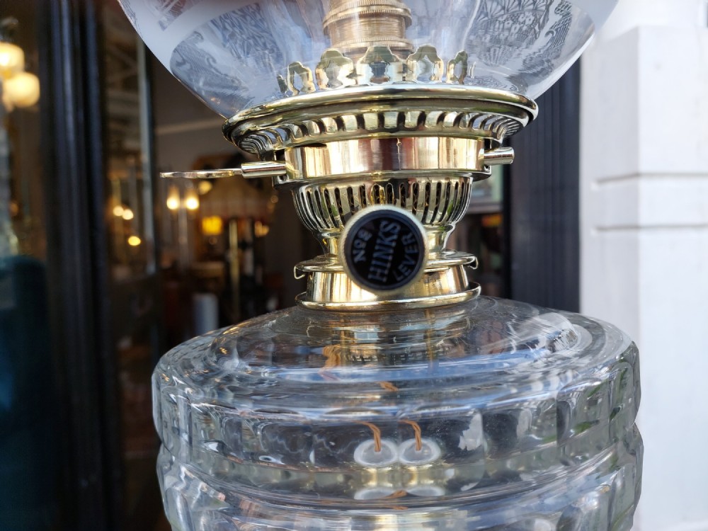 A Victorian brass oil lamp featuring a fluted Corinthian column base, a clear glass reservoir, and an etched spherical glass shade. View VII